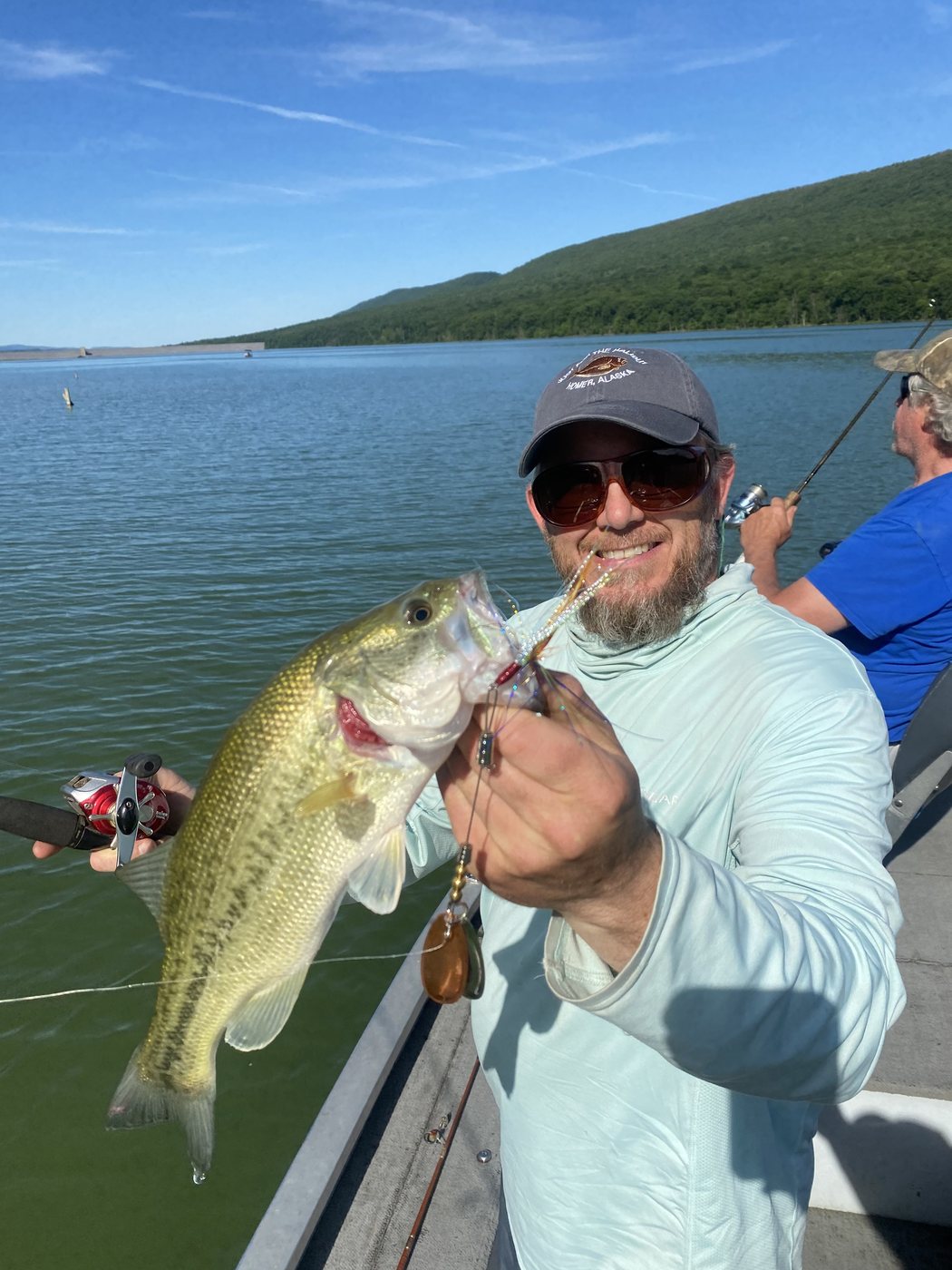A largemouth bass taken from the boat, gold blade still in its jaw