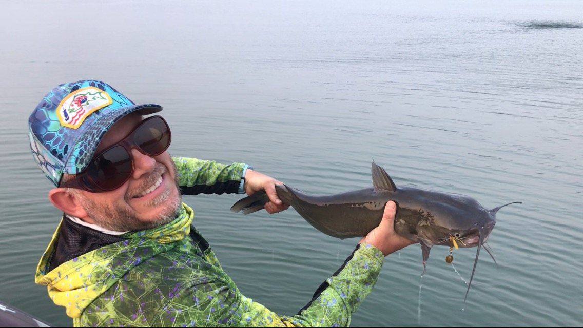 A channel catfish, chartreuse tail still in the corner of its mouth