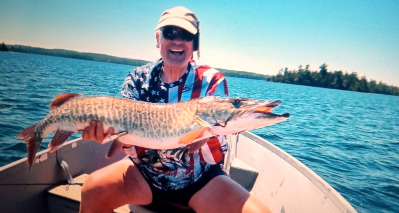 A long muskellunge held across the gunwale of a boat.