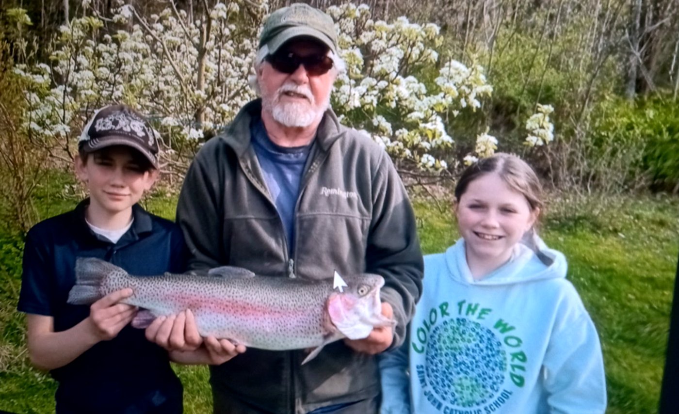 A big rainbow trout shared between two young anglers